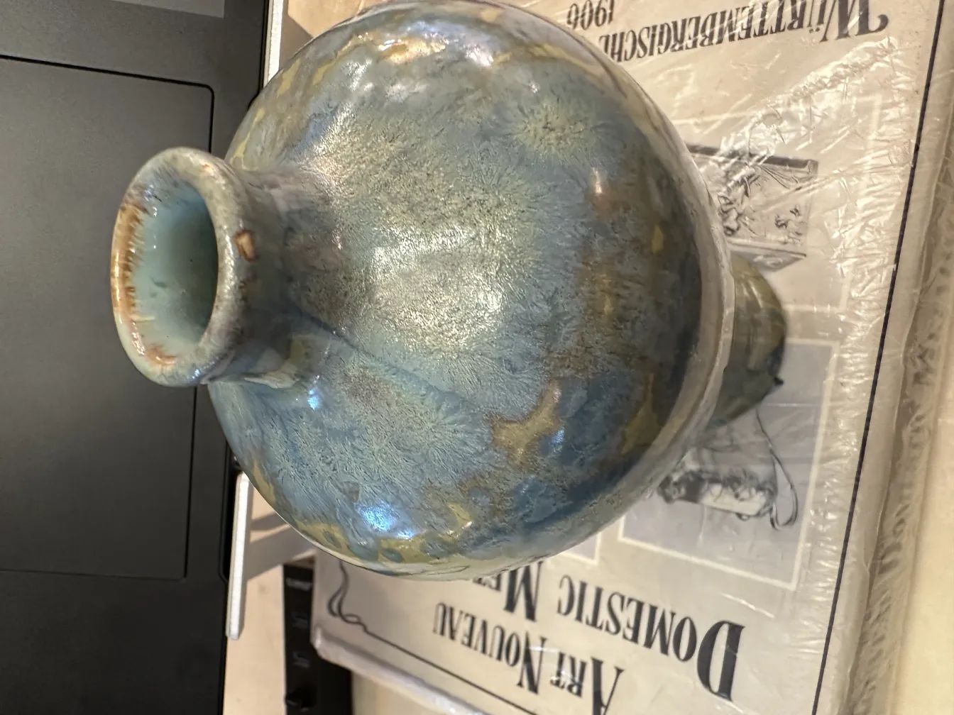 Vase en céramique ancienne avec des tons bleus et verts, décorations subtiles.