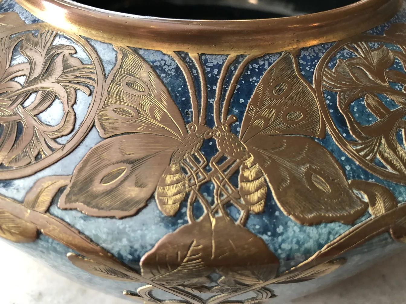 Antica ceramica decorata con oro e dettagli di farfalle su uno sfondo blu.