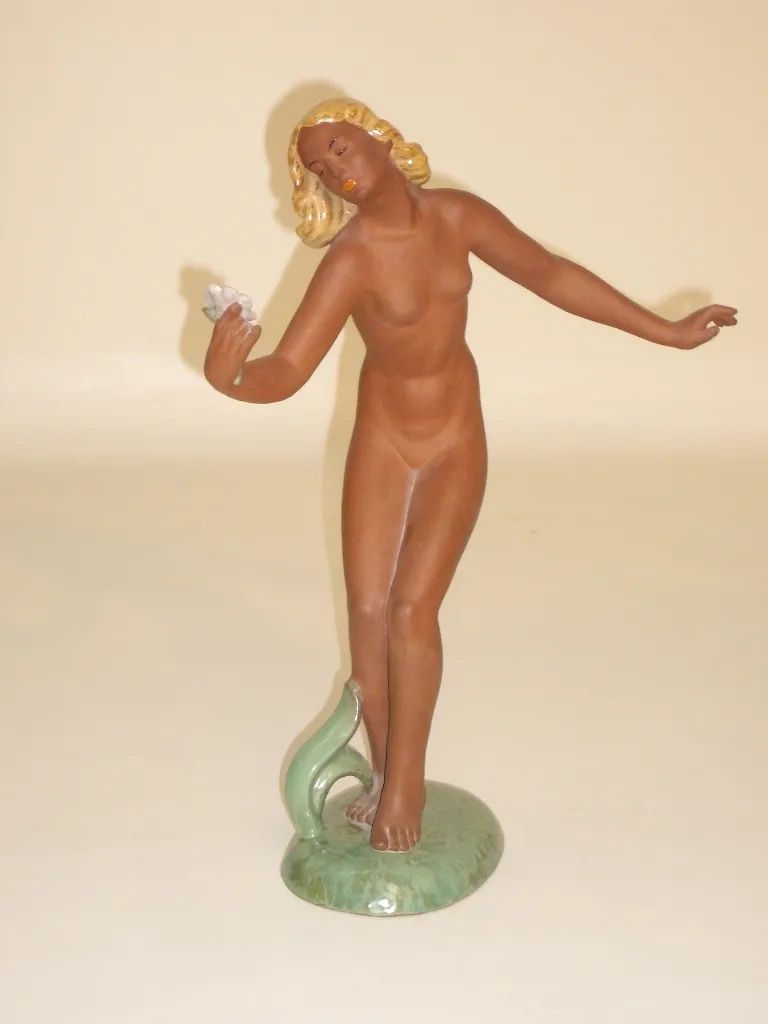 Scultura in ceramica antica, figura femminile in posa elegante.