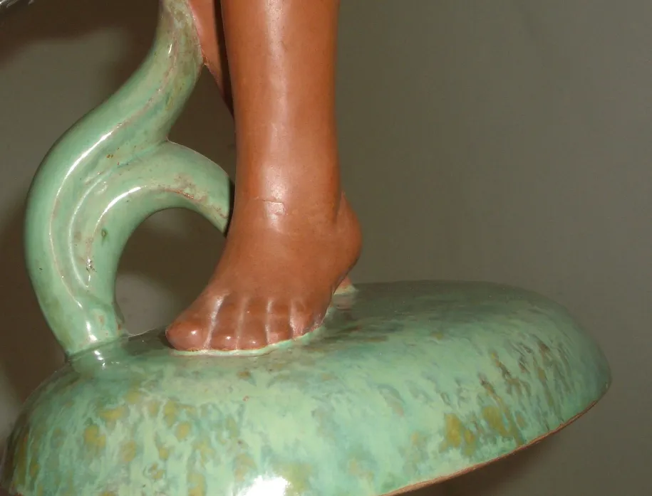 Escultura de cerâmica antiga com detalhes em verde e terracota.