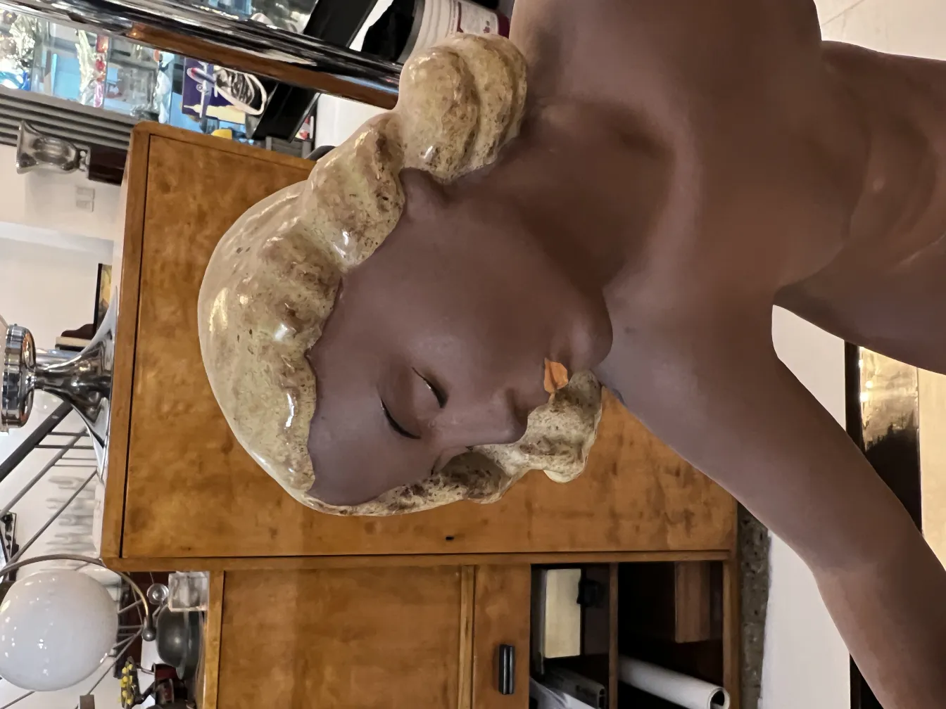 Portrait in antique ceramic with decorative details and serene expression, background with simple furniture.