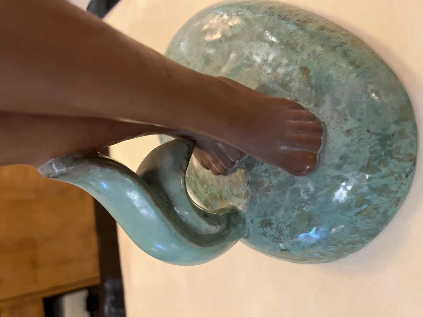 Céramique antique avec un design sculptural et un pied décoratif, vert avec des nuances.