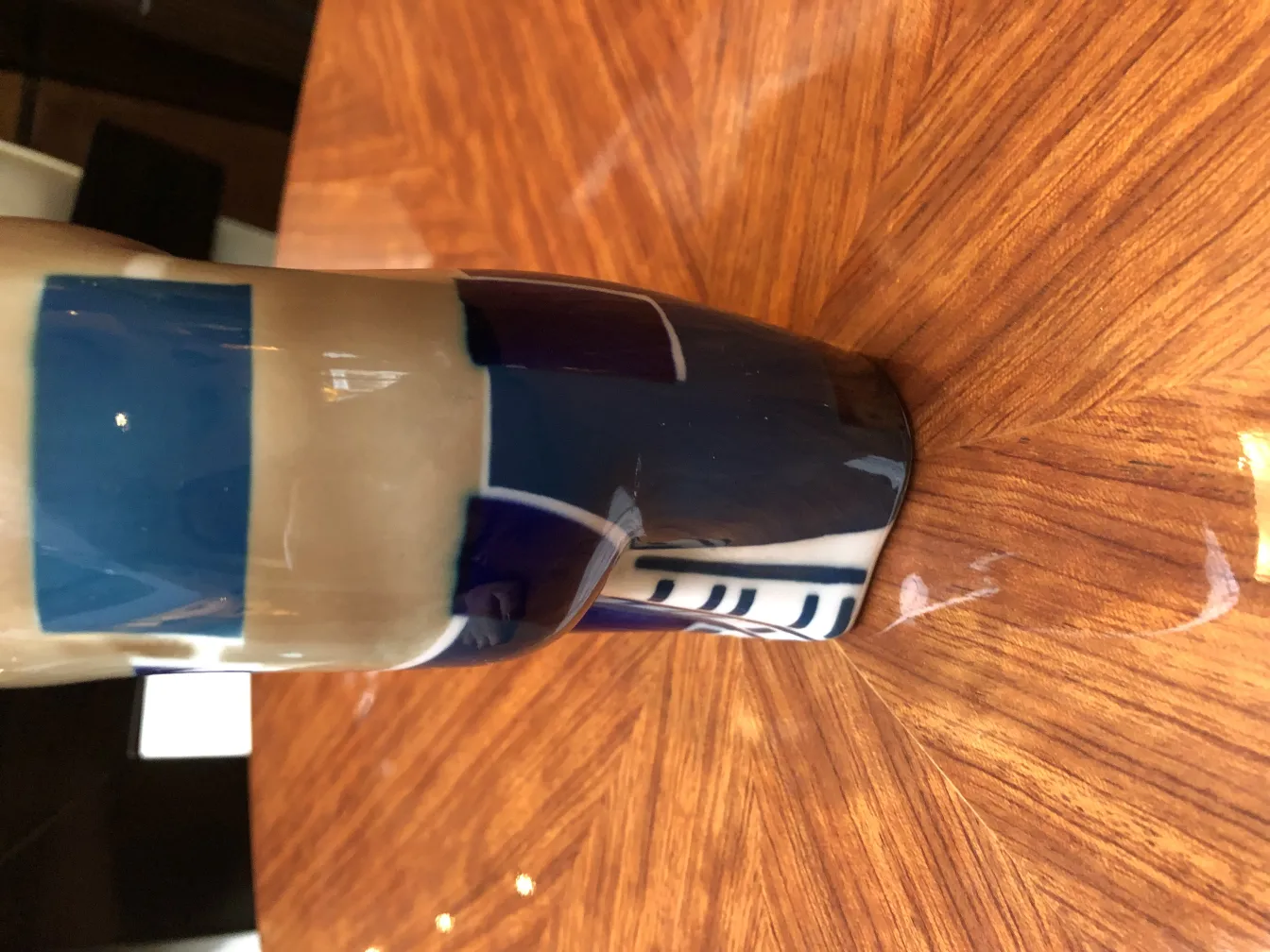 Antike dekorative Keramik mit blauen Mustern auf hellem Hintergrund, auf einem Holztisch platziert.