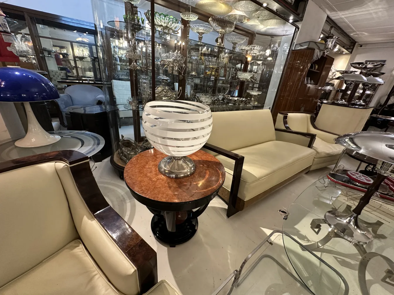 Lámpara de mesa antigua con diseño circular y base plateada en un entorno de antigüedades.