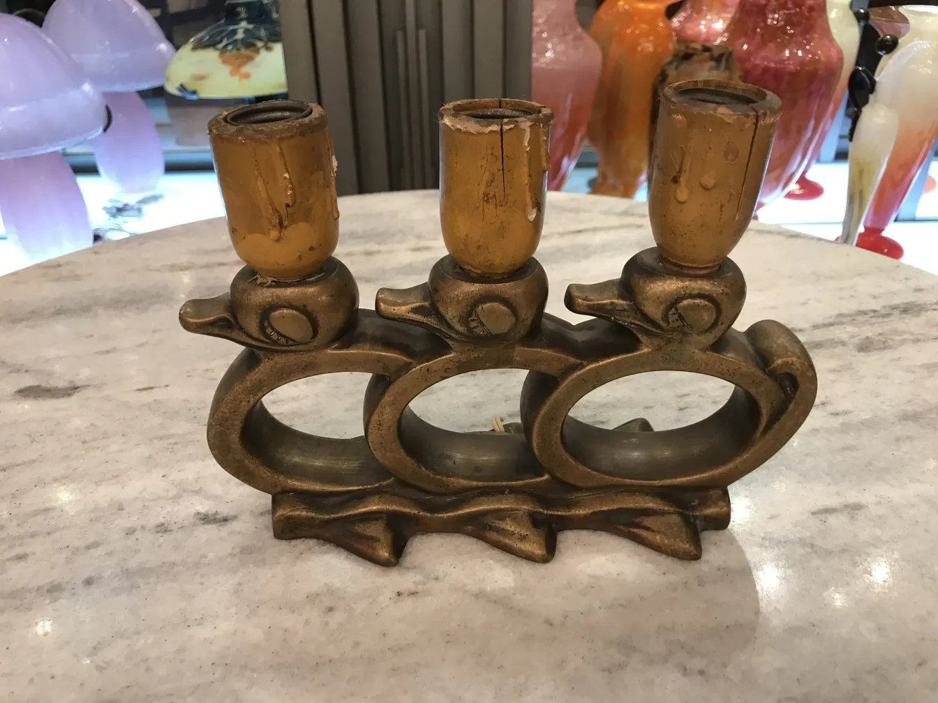 Antiga luminária de mesa com três braços, design artístico e ambiente aconchegante.