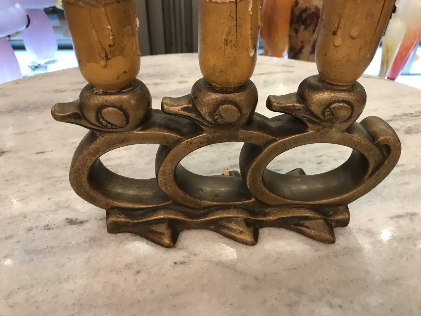 Lámpara de mesa antigua con base en forma de ave, detalles decorativos y ambiente acogedor.