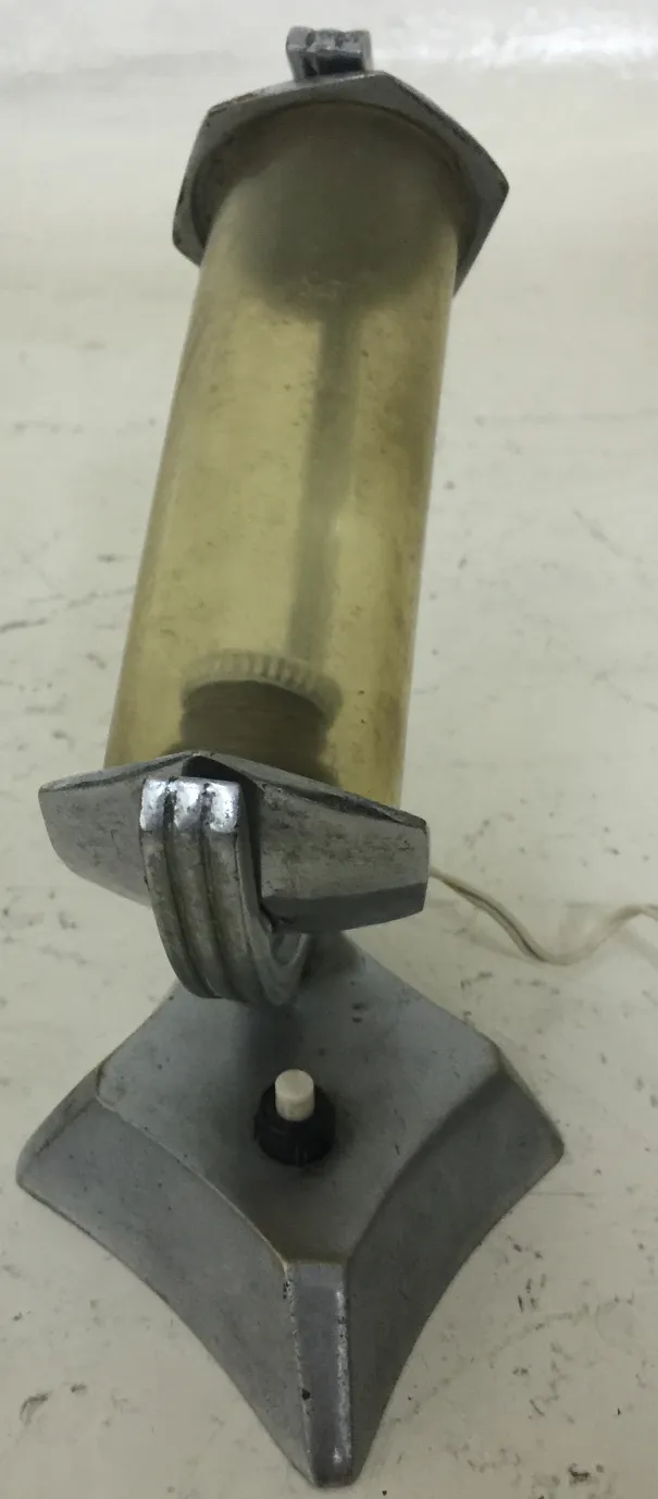 luminária de mesa antiga com formato cilíndrico e base decorativa, ambientada em um espaço aconchegante