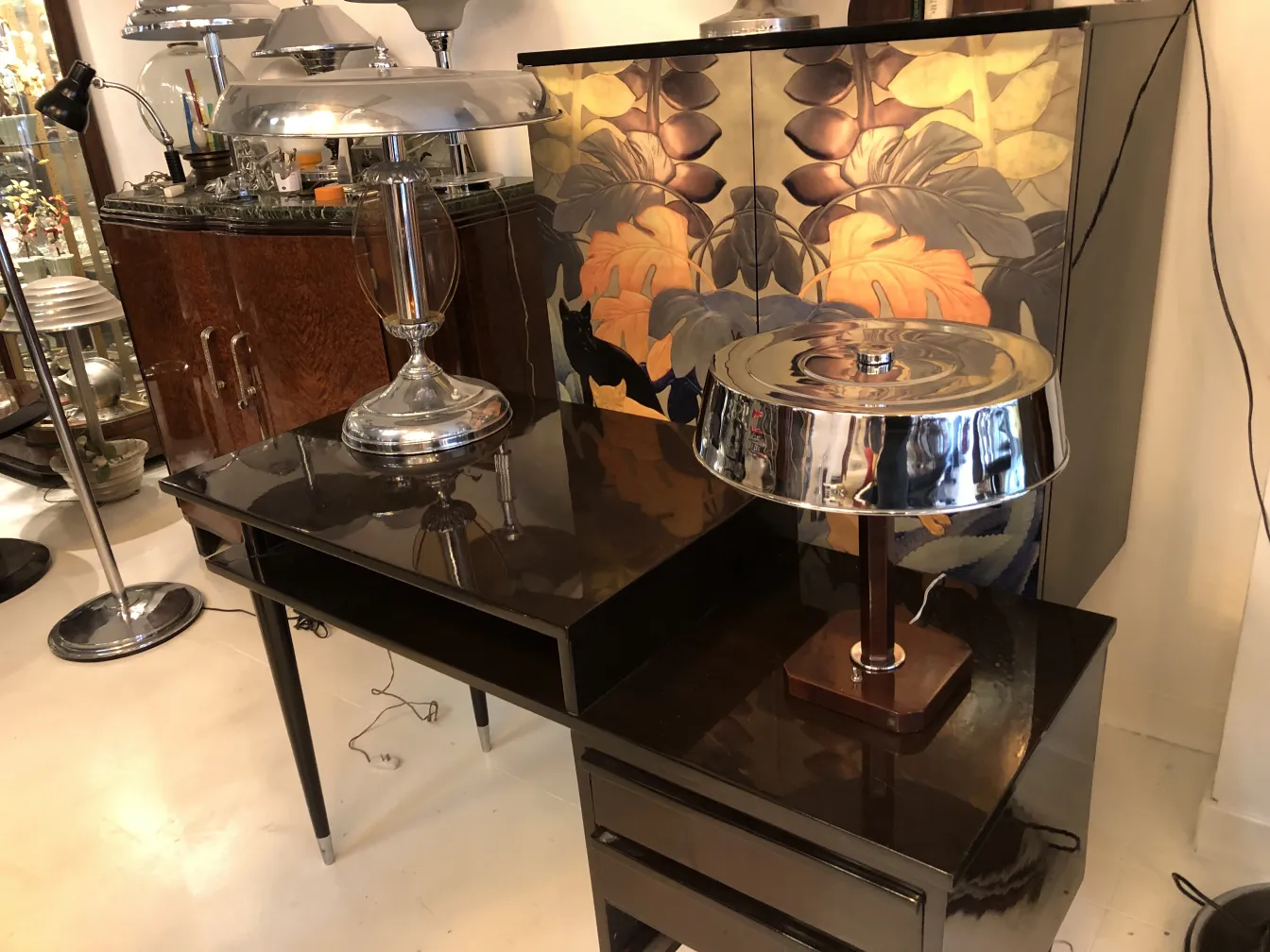 Antiga luminária de mesa brilhante sobre uma mesa preta com fundo decorativo.