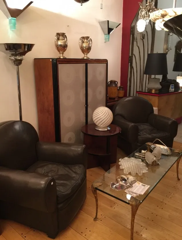 Antiga luminária de mesa esférica em um ambiente acolhedor com poltronas de couro.