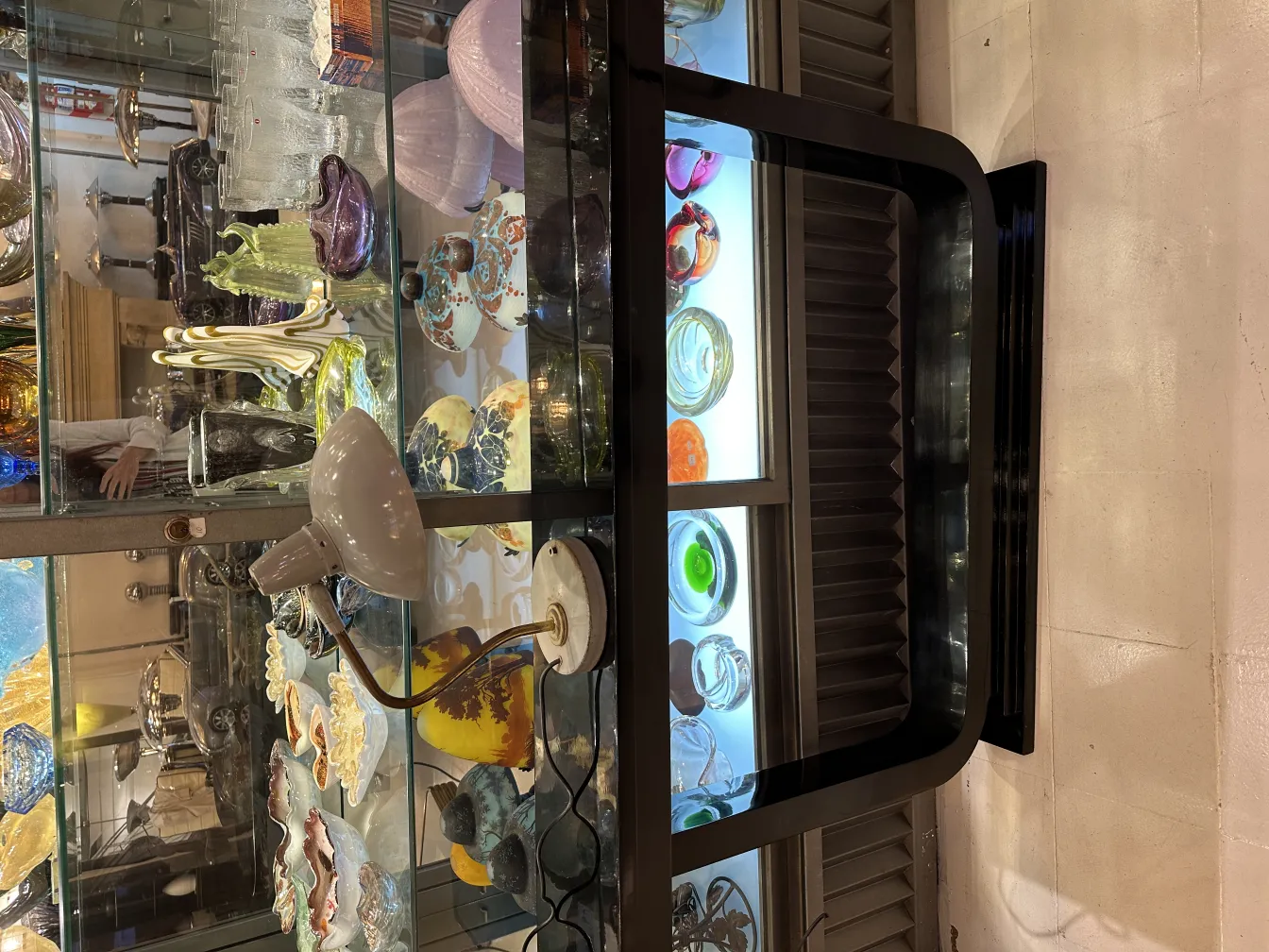 lampara de mesa antigua con luz suave y base artística, rodeada de objetos decorativos