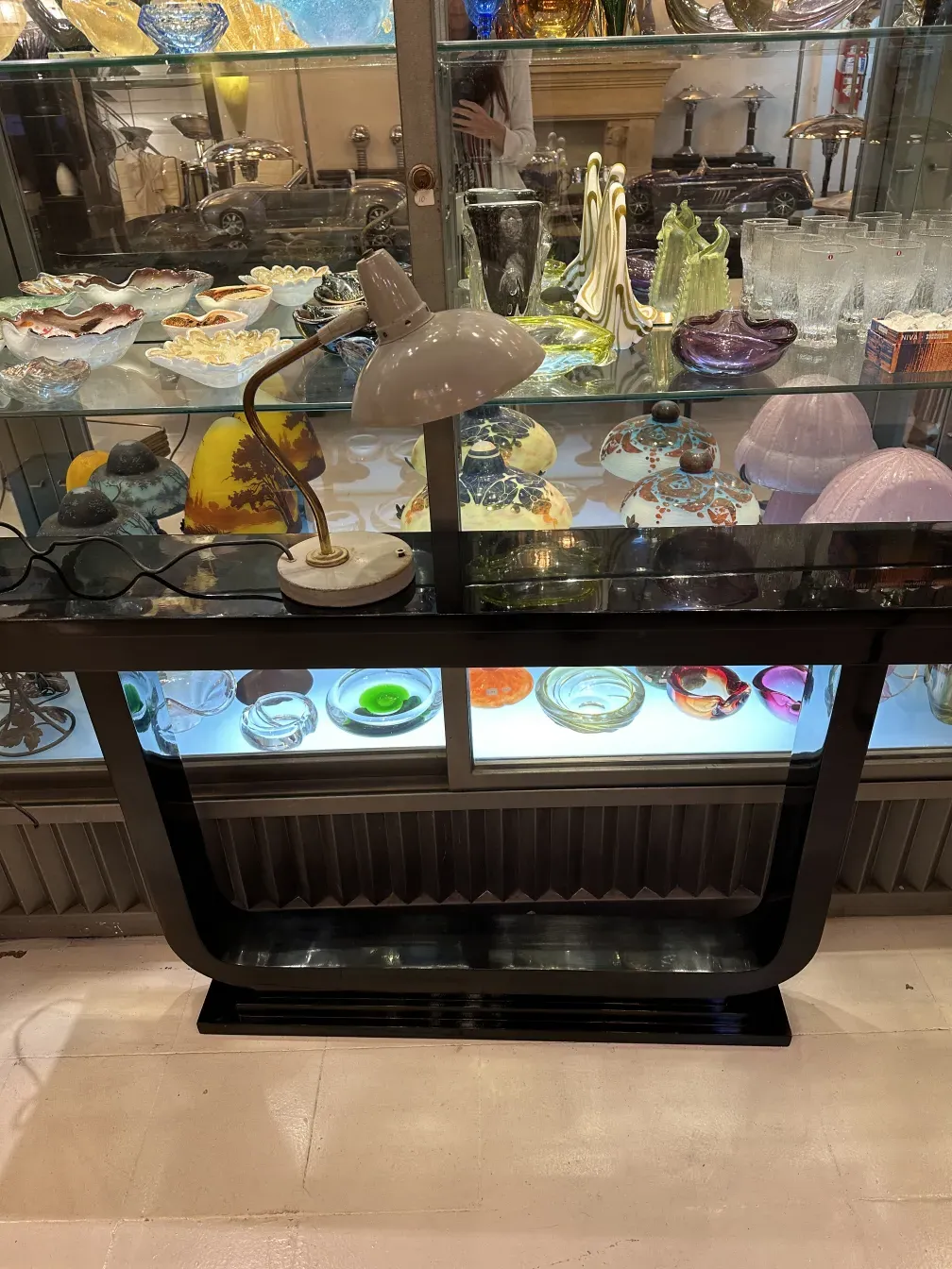 Старинная настольная лампа Сержа Мули с изогнутым дизайном, расположенная на столе с декоративными предметами.