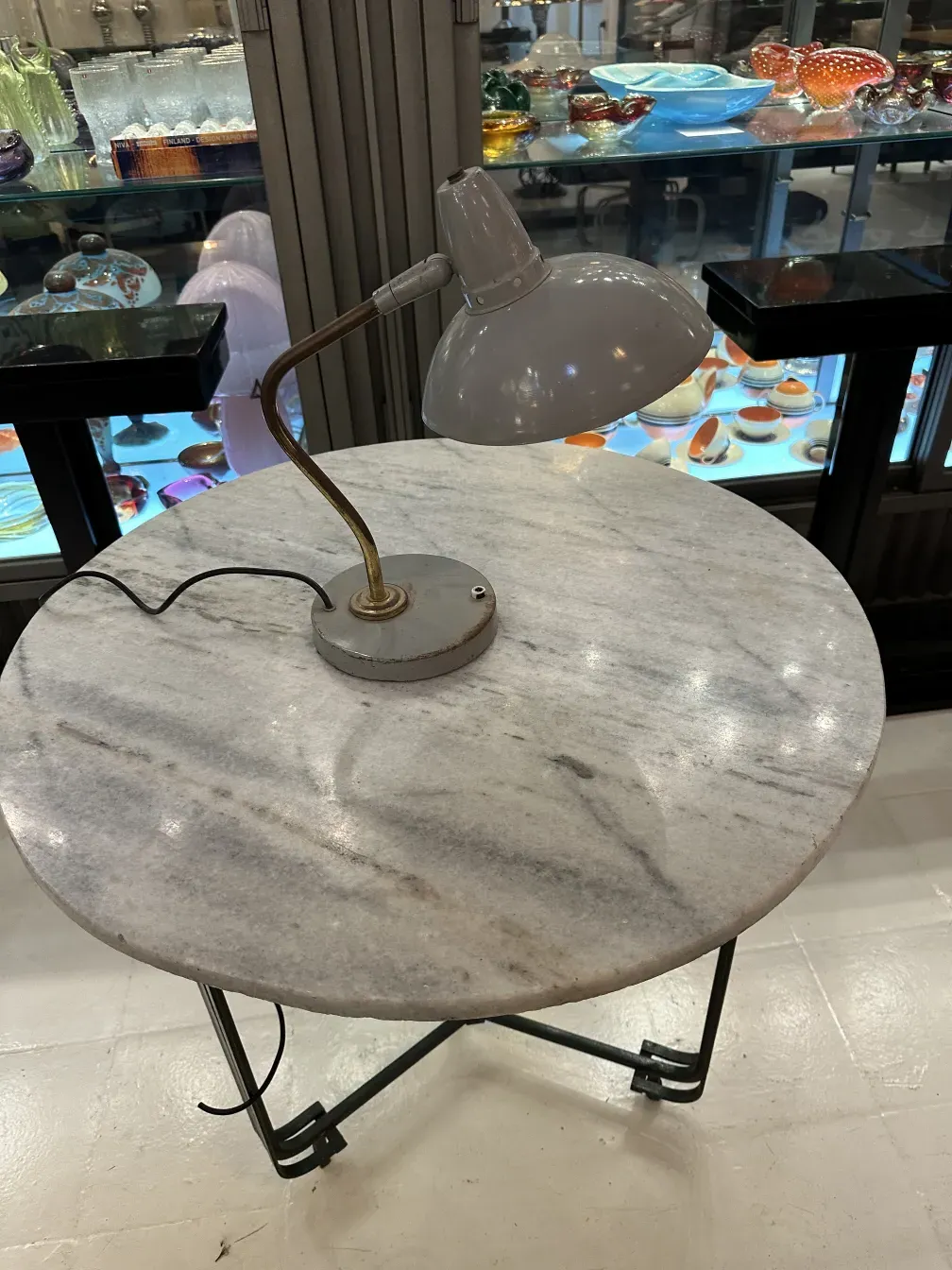 Antigua lámpara de mesa de Serge Mouille con base curva sobre mesa redonda, ambiente acogedor.