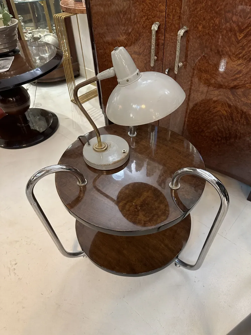 Antique table lamp with a circular base and white shade in an elegant setting.