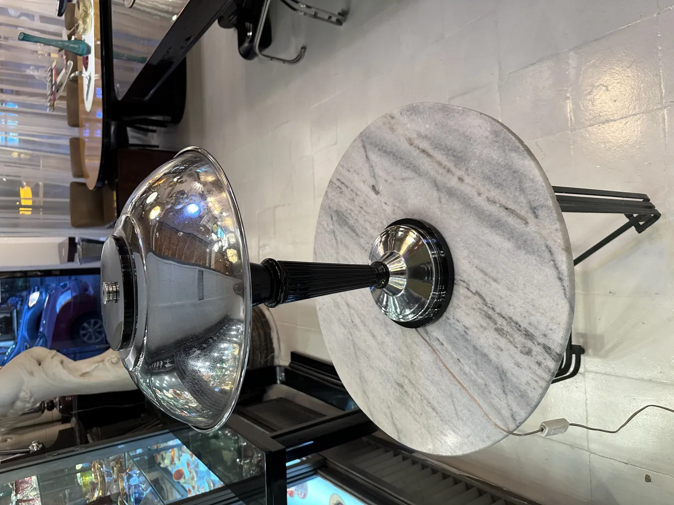 Lampada da tavolo antica con base lucida e paralume rotondo in un ambiente elegante.