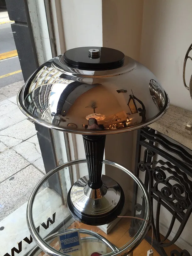 antigua lámpara de mesa con sombra metálica y detalles pulidos, en un ambiente acogedor.