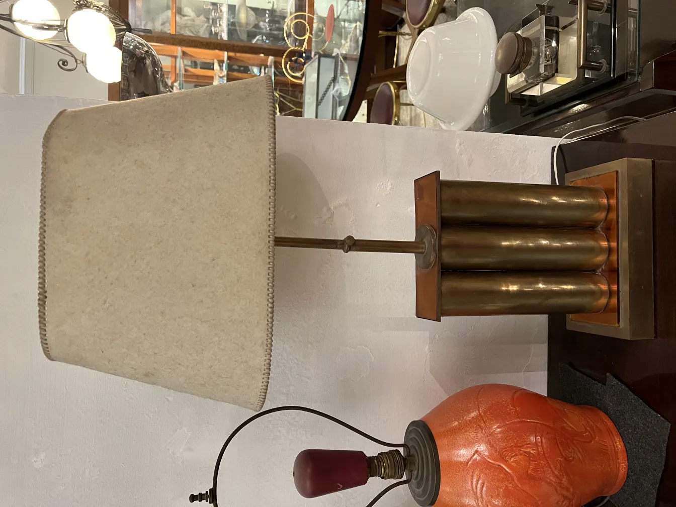 Lampada da tavolo antica con base unica e paralume beige, in un ambiente classico.