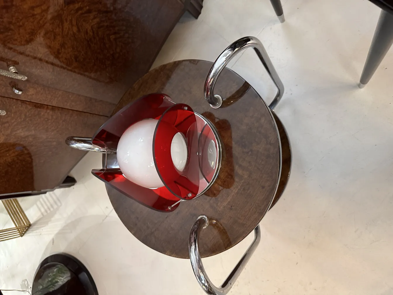 antike Tischlampe mit runder Basis und roten Details neben einem Holztisch