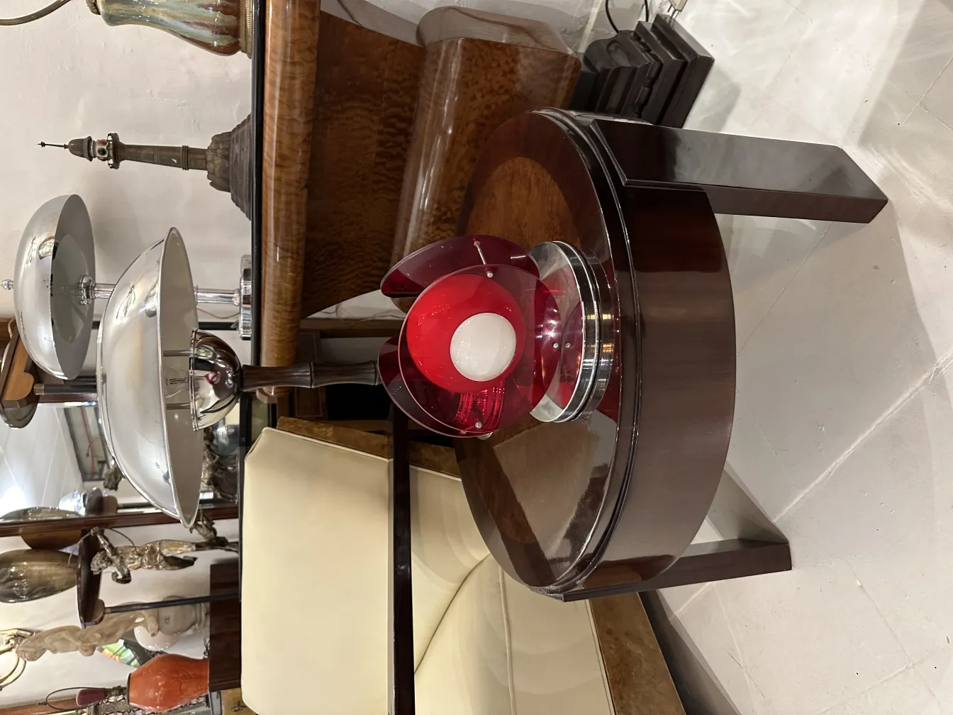 Luminária de mesa antiga com design vermelho e luz branca. A base elegante é parte de um ambiente de antiguidades.