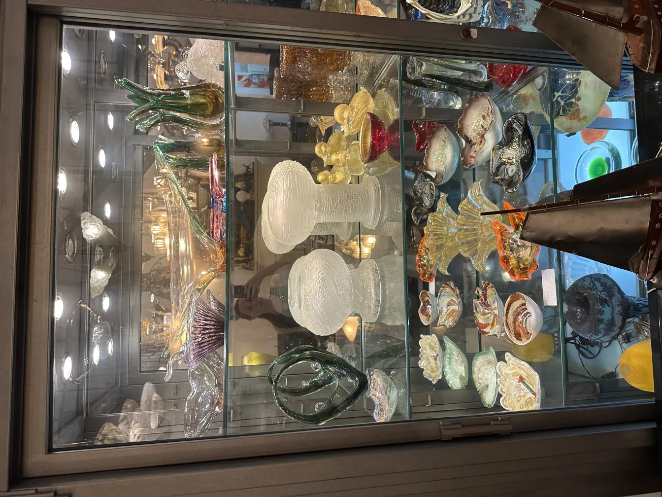 antike tischlampe in vitrine mit bunten dekorationen