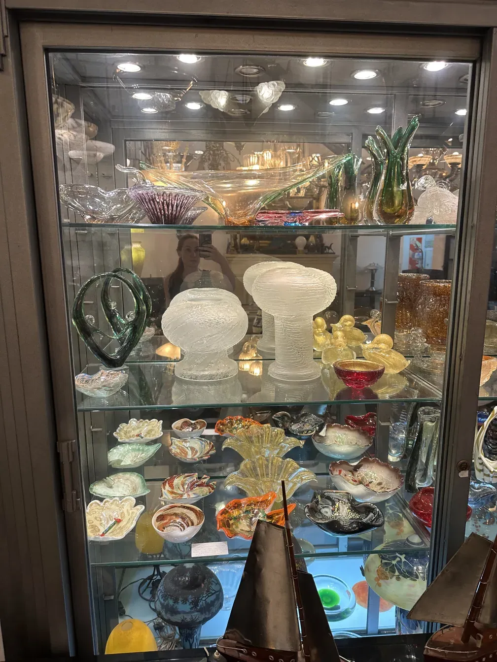 Lampada da tavolo antica con design in vetro, circondata da altri oggetti decorativi.