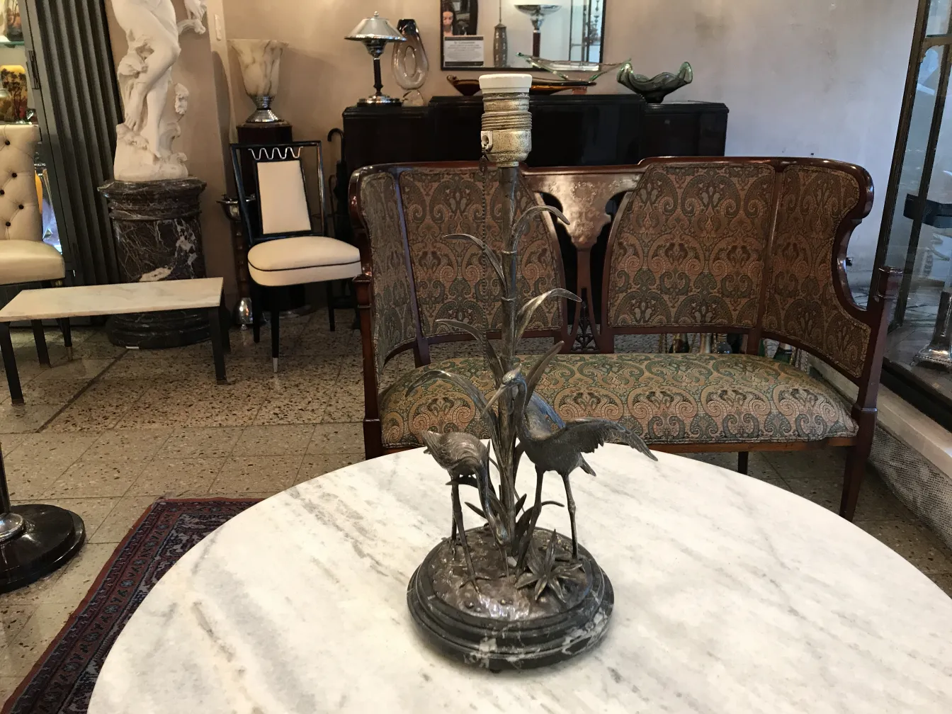 Antique table lamp with bird decoration in an elegant setting.