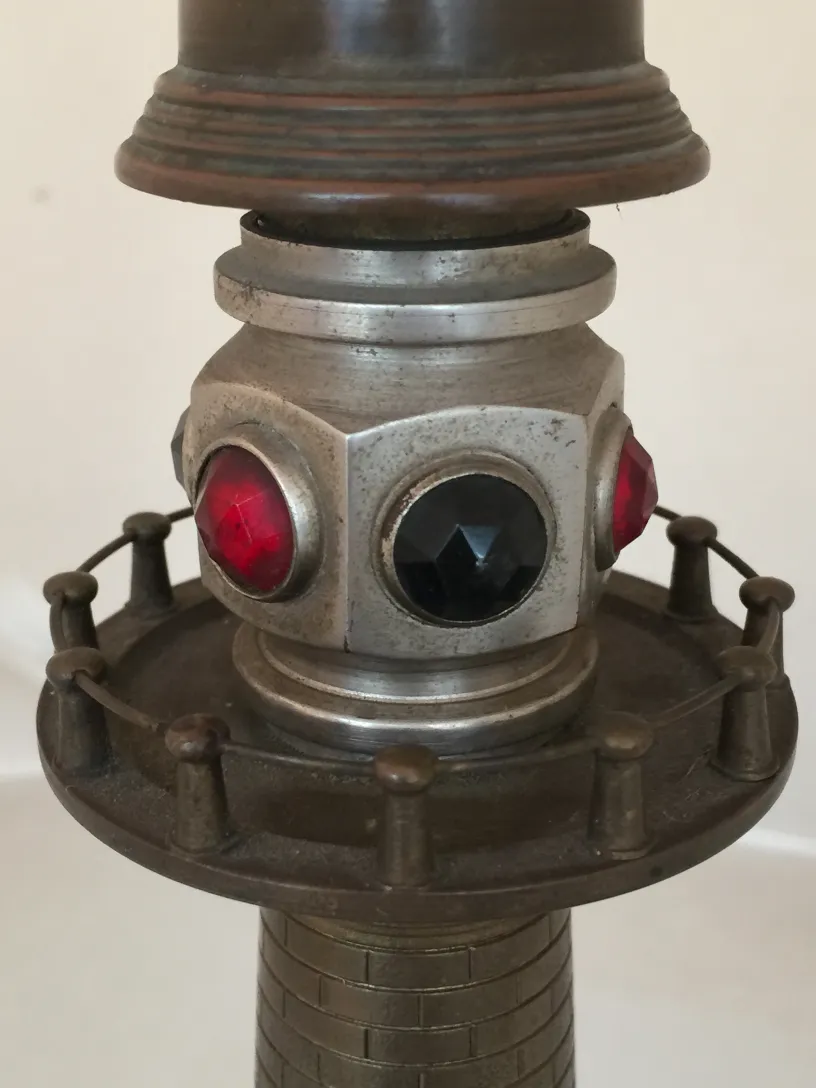 Détail d'une lampe de bureau ancienne avec accents de bijoux rouges et noirs à la base, décorations classiques