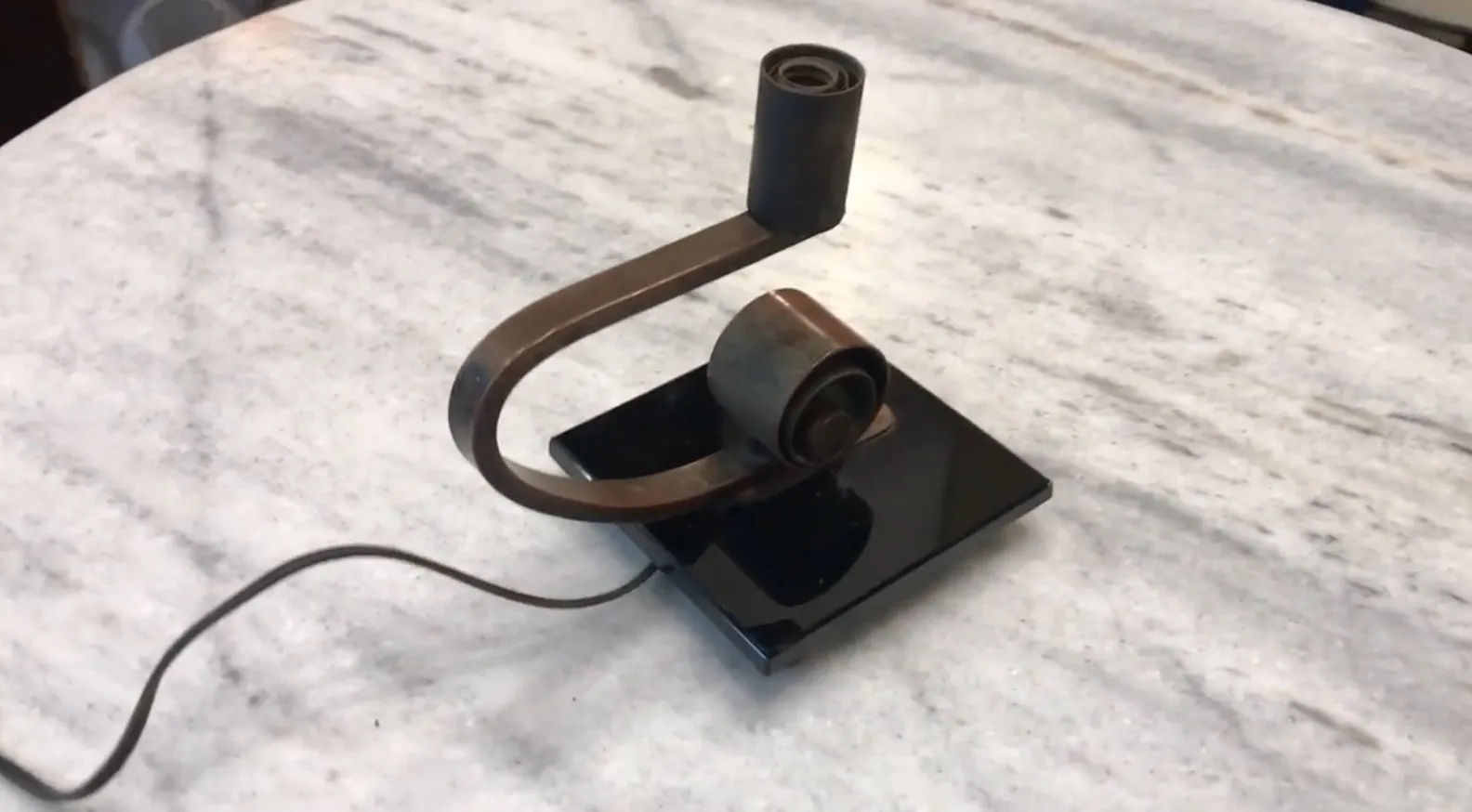 Lampada da tavolo antica con base nera e dettagli arrotondati.