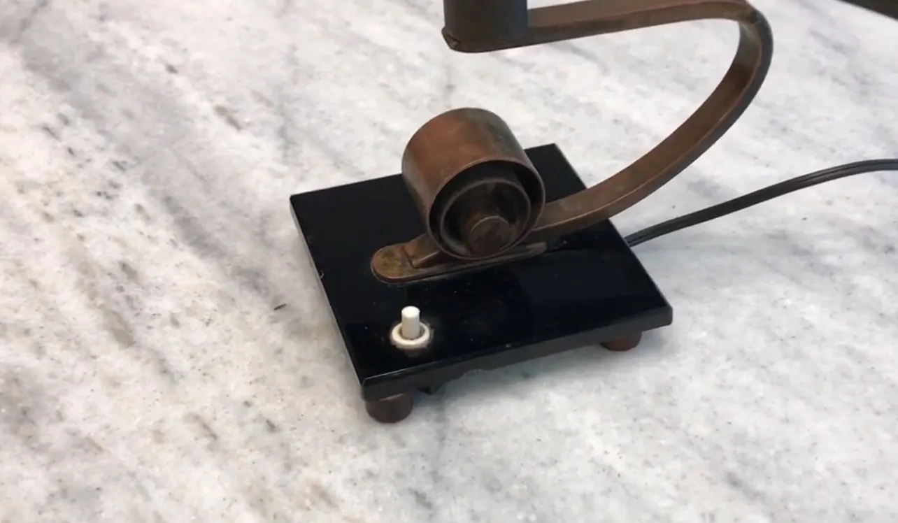 Lámpara de mesa antigua con base negra y detalles metálicos, ideal para decoración.