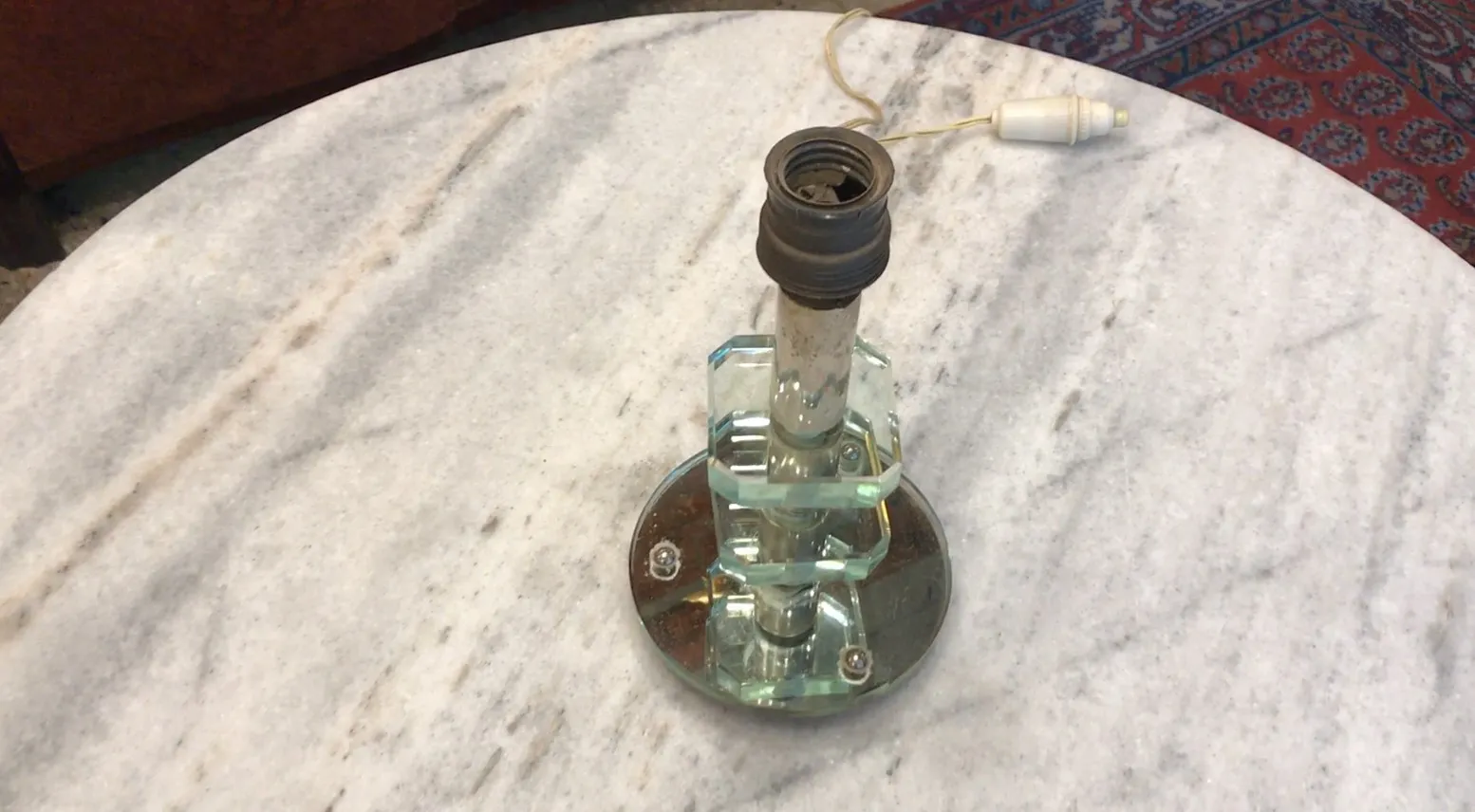 Antique table lamp with glass base, illuminating a decorative table.