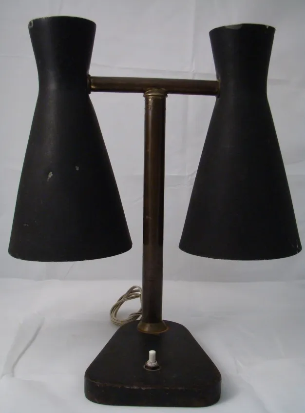 Lámpara de mesa antigua con dos pantallas negras en un entorno minimalista.