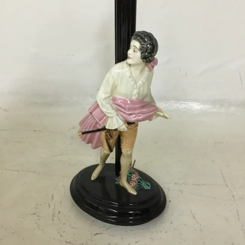 Luminária de mesa antiga com figura segurando um guarda-chuva em um ambiente clássico.