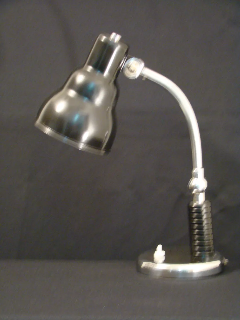 lampe de bureau ancienne avec finition métallique et base noire, dans un environnement sombre