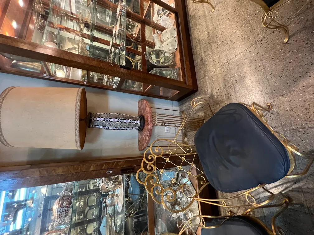 lampe de bureau ancienne avec base décorative et abat-jour beige, dans un environnement de meubles élégants