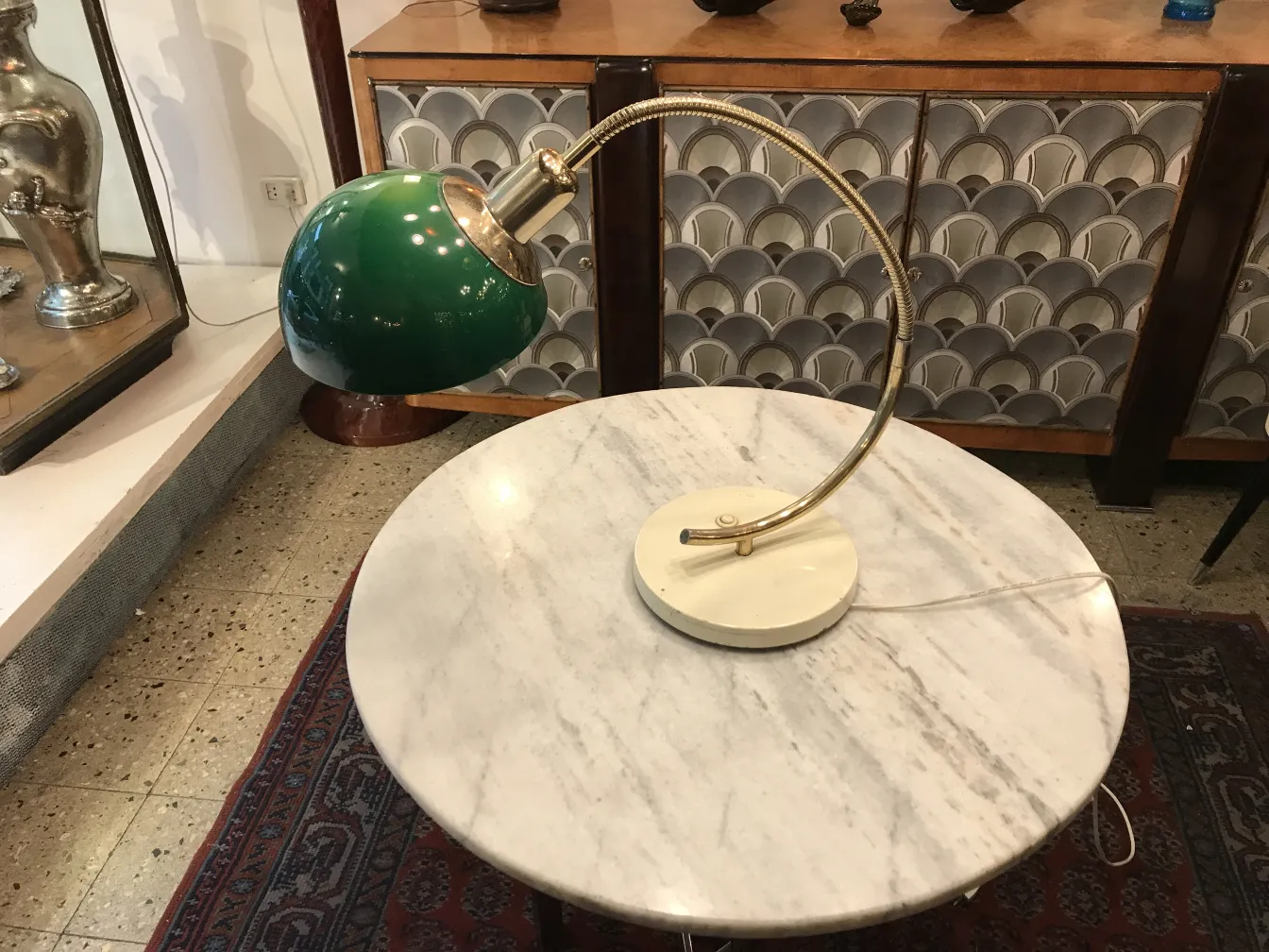 Lampe de bureau ancienne avec base claire et abat-jour vert dans un cadre accueillant.