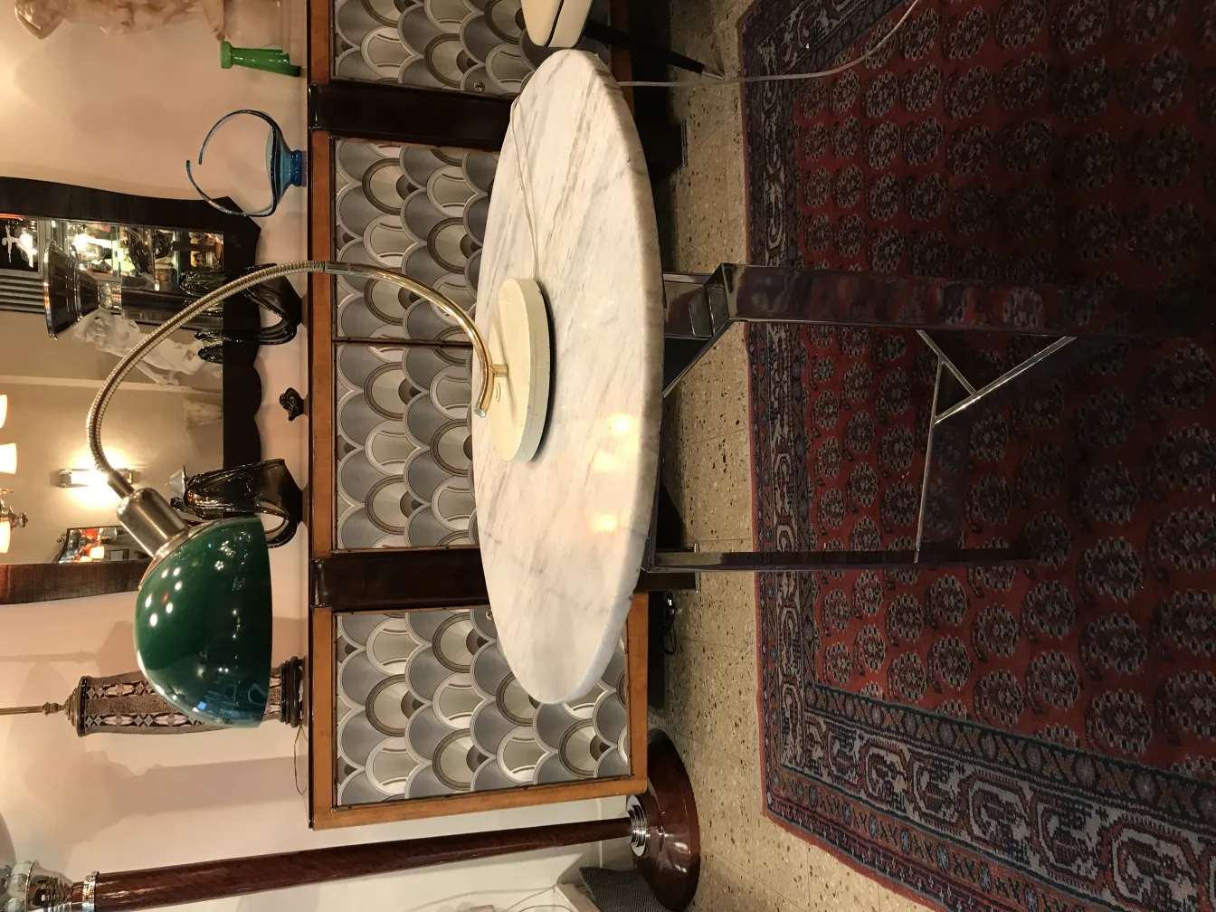 Luminária de mesa antiga com base redonda e braço flexível em um ambiente vintage com tapete oriental.