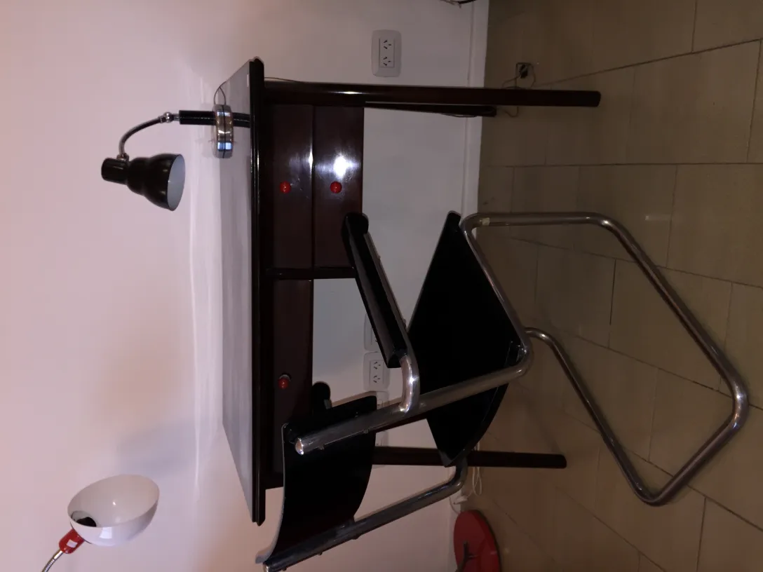 antique table lamp with articulated arm and white light, on a work table with red drawers and a black chair