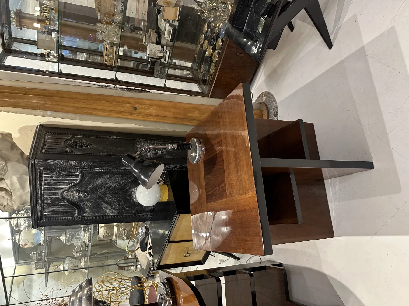 Lampada da tavolo antica con base nera e dettagli in metallo. Sfondo con scaffali di antiquariato.