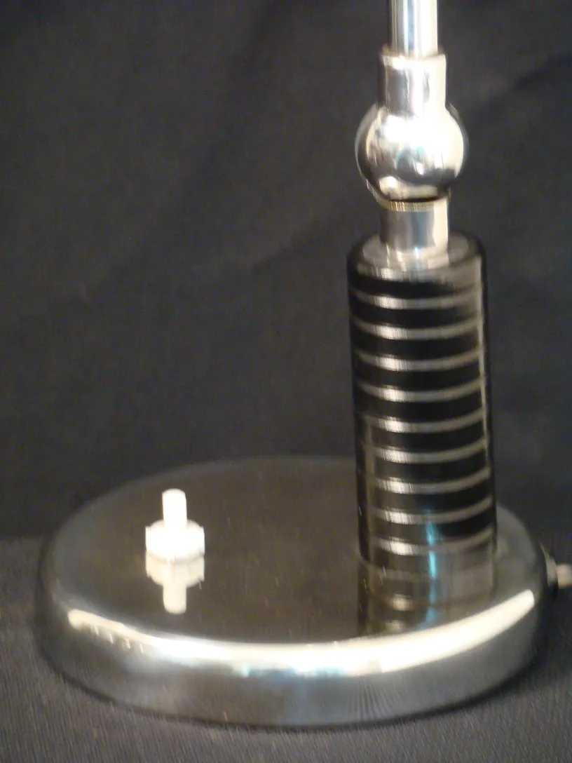 Antike Tischlampe mit runder Basis und elegantem Design in einer dunklen Umgebung.