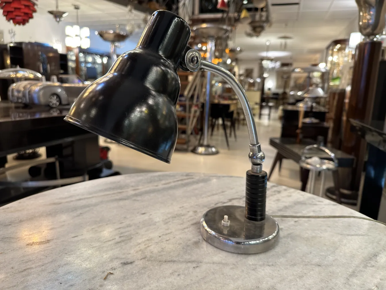 Lampada da tavolo antica con base metallica e paralume nero, in un ambiente decorativo.