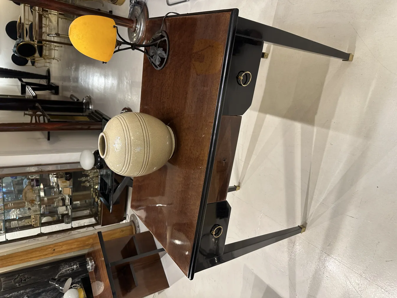 Antique table lamp with decorative base and yellow light, set in an antique environment.