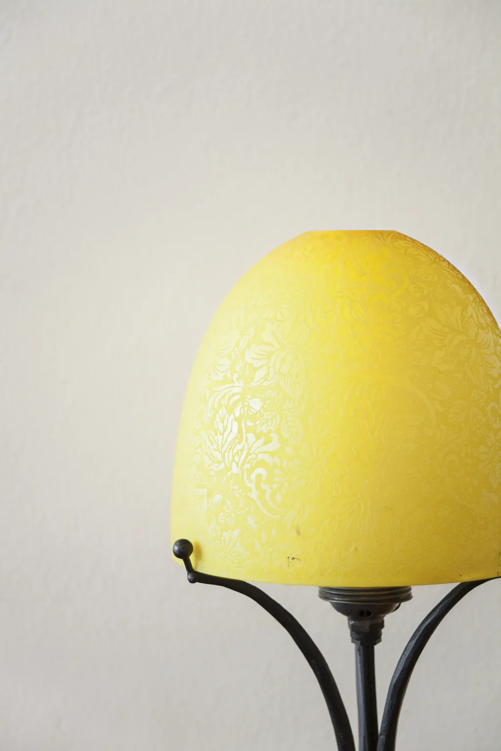 Antique table lamp with decorative yellow shade, neutral background.