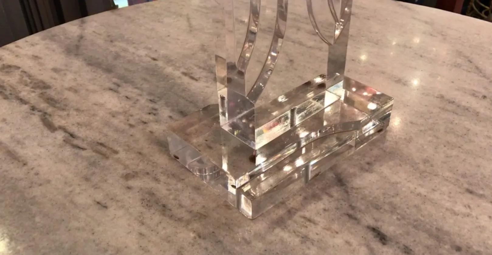 Lámpara de mesa antigua con base transparente sobre una superficie clara, ambiente elegante.