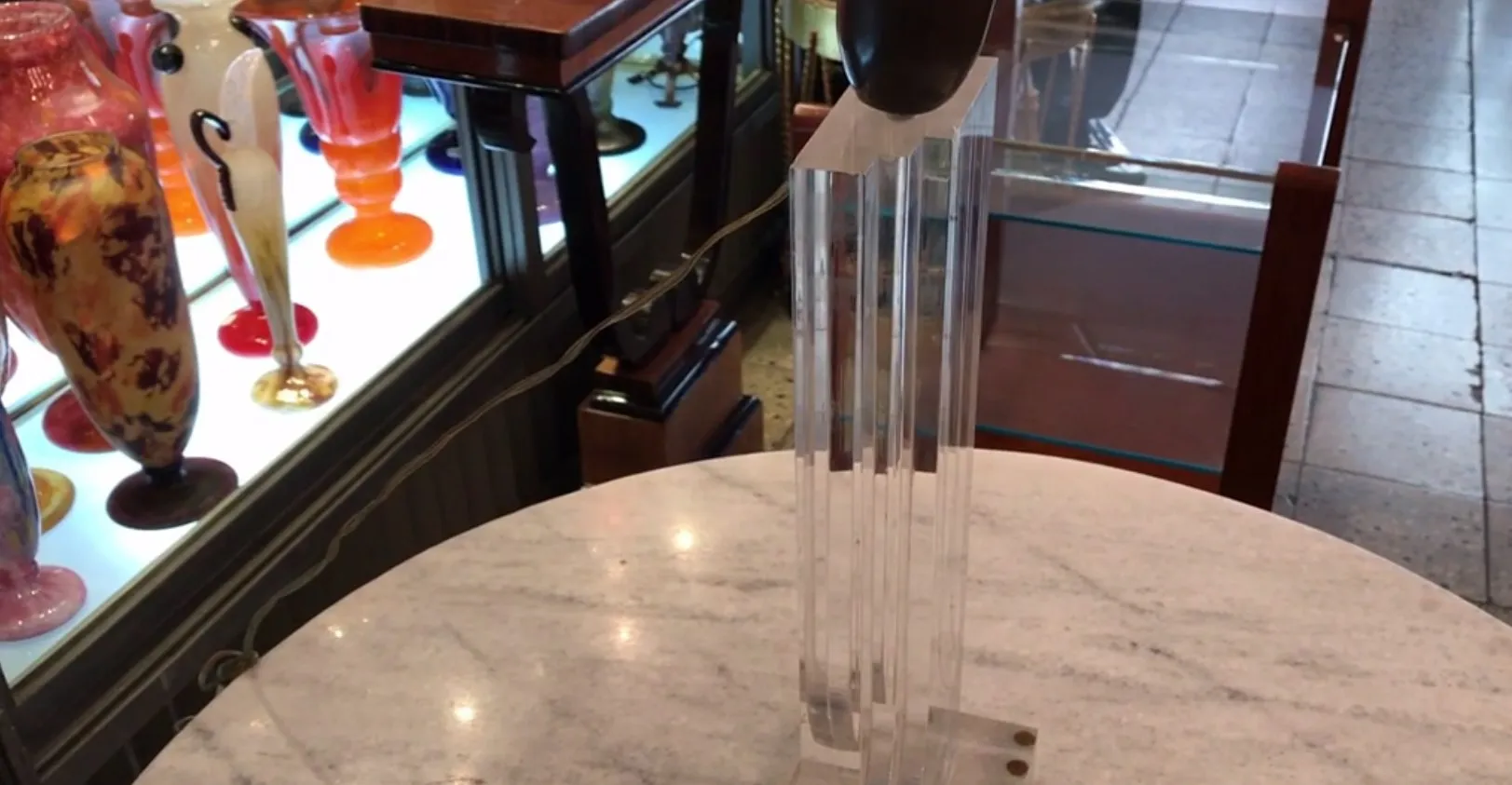 Una lampada da tavolo antica con design scultoreo elegante e linee moderne, circondata da oggetti decorativi in un ambiente rilassante.