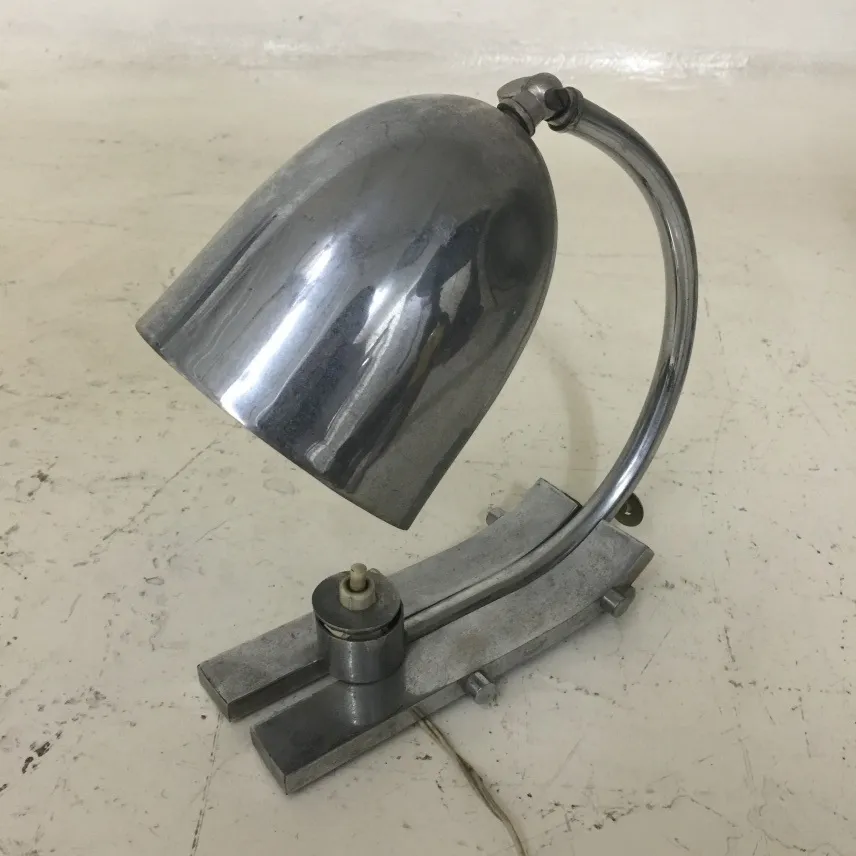 antique shiny table lamp with a sleek base and curved shade, placed on a light surface