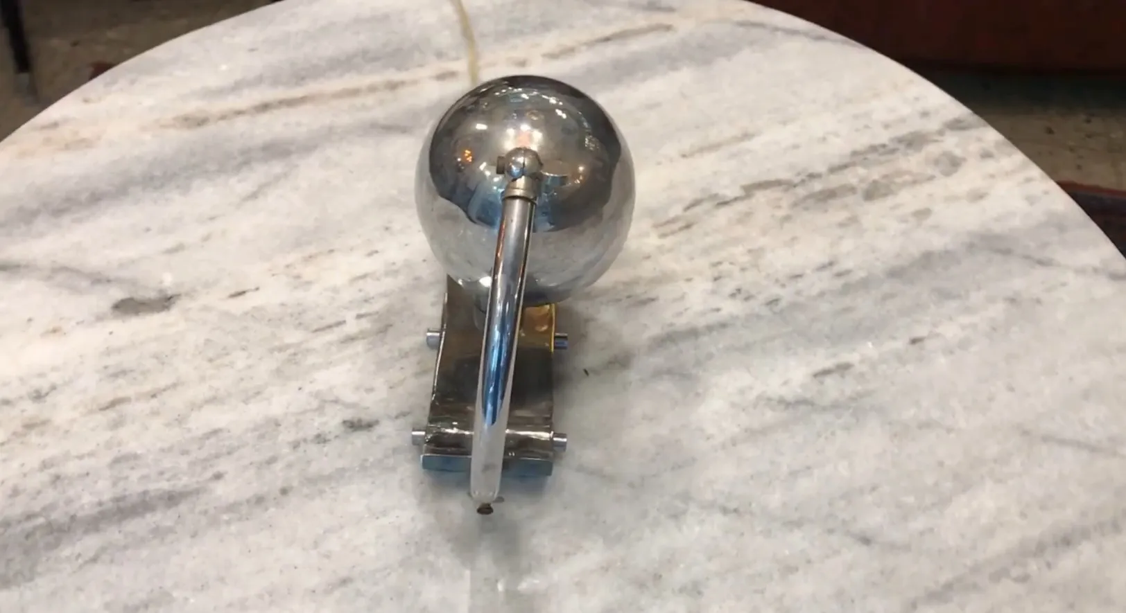 Lampada da tavolo antica con base metallica e sfera luminosa, su un tavolo.