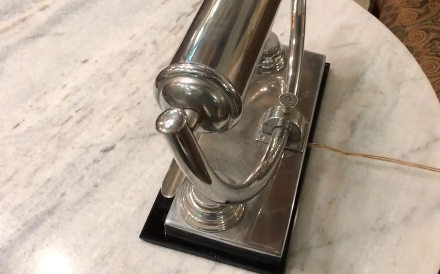 Lampe de bureau antique brillante avec un design élégant, fond en marbre clair.