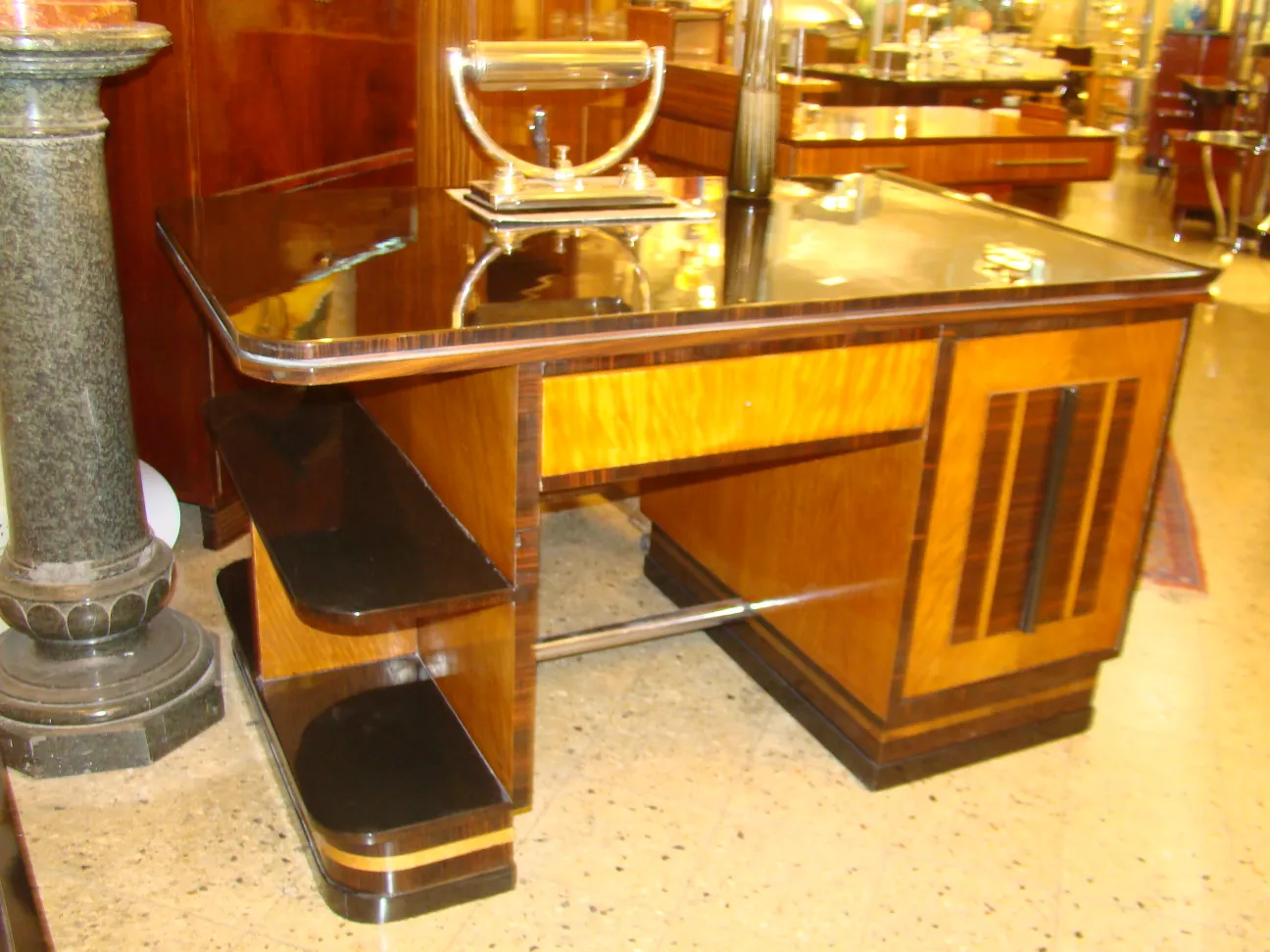 독특한 디자인의 오래된 테이블 램프가 우아한 책상을 비추고 있습니다.