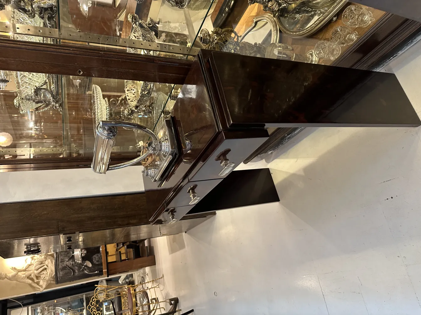 Lámpara de mesa antigua con base pulida y detalles brillantes, rodeada de otros objetos decorativos.