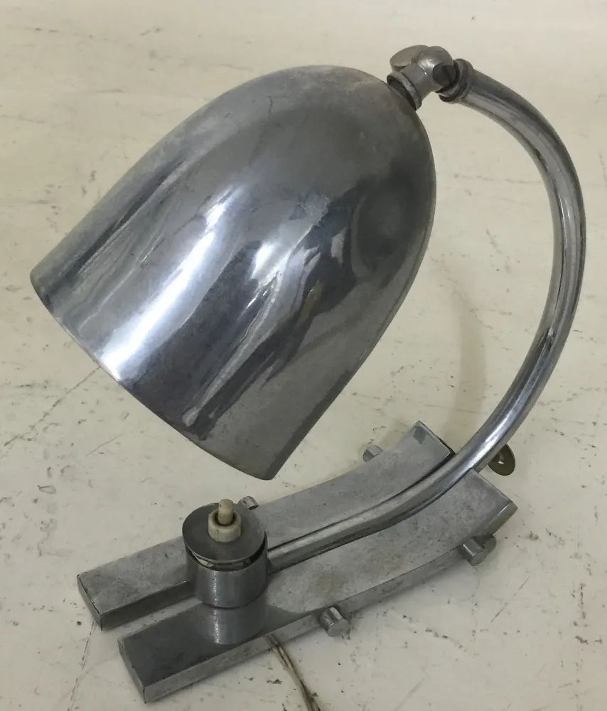 Lampe de bureau ancienne avec un abat-jour distinctif et une base élégante dans un cadre chaleureux.