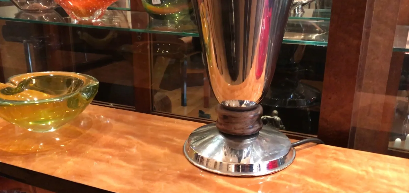 Lámpara de mesa antigua con base brillante y soporte oscuro.